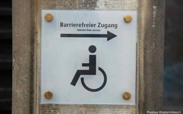 Schild an einer Wand, das auf einen barrierefreien Zugang hinweist.