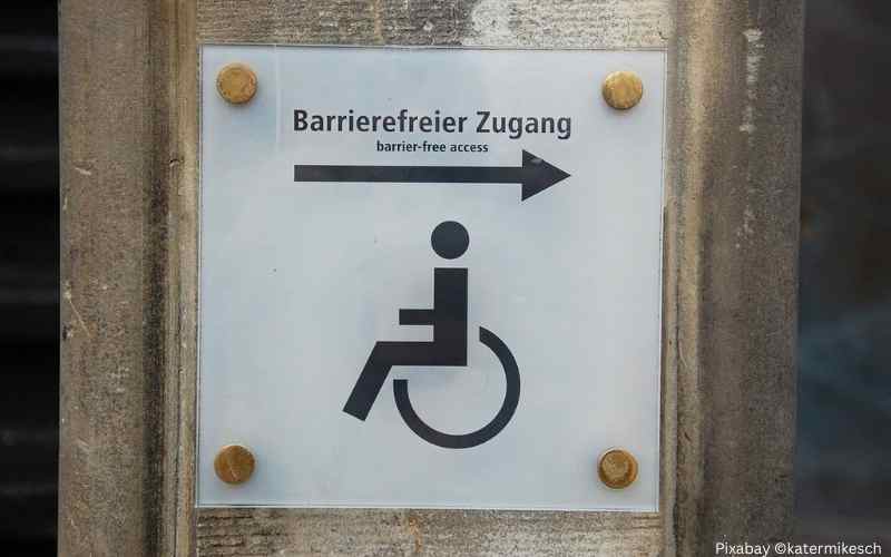 Schild an einer Wand, das auf einen barrierefreien Zugang hinweist.